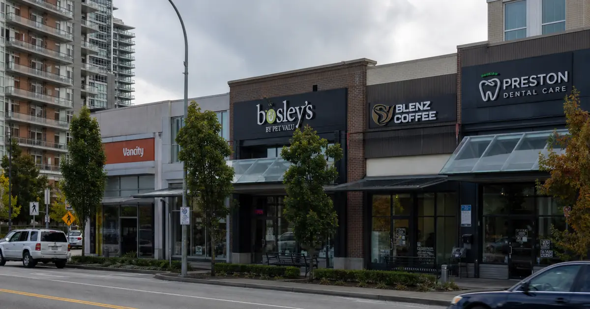 Daytime Surrey-style commercial plaza with storefront fascia signs along the sidewalk